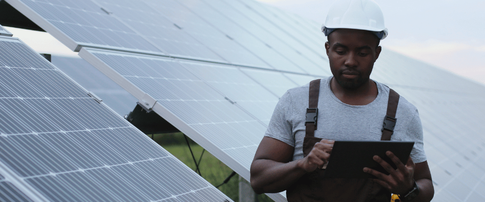 Building-worker-looking-at-tablet-in-front-of-solar-panels