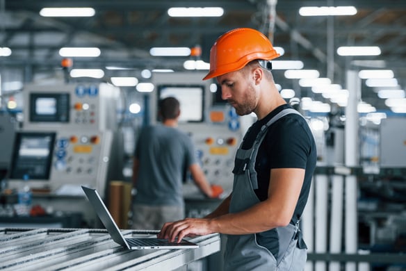 man-uses-laptop-in-factory-wearing-hard-hat-2026-09-22-03-02-51-utc