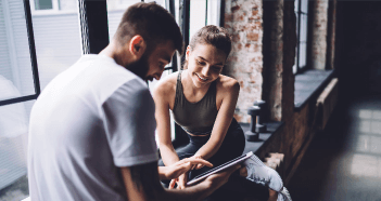 Man And Woman In Gym Using Tablet