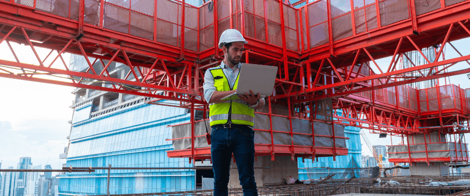 Engineer-using-laptop-in-front-of-building-construction