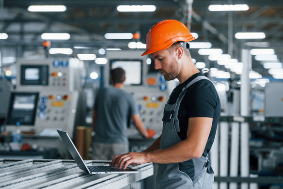 man-uses-laptop-in-factory-wearing-hard-hat-2026-09-22-03-02-51-utc